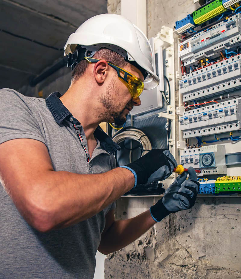 An electrician working on a switchboard with fuses.