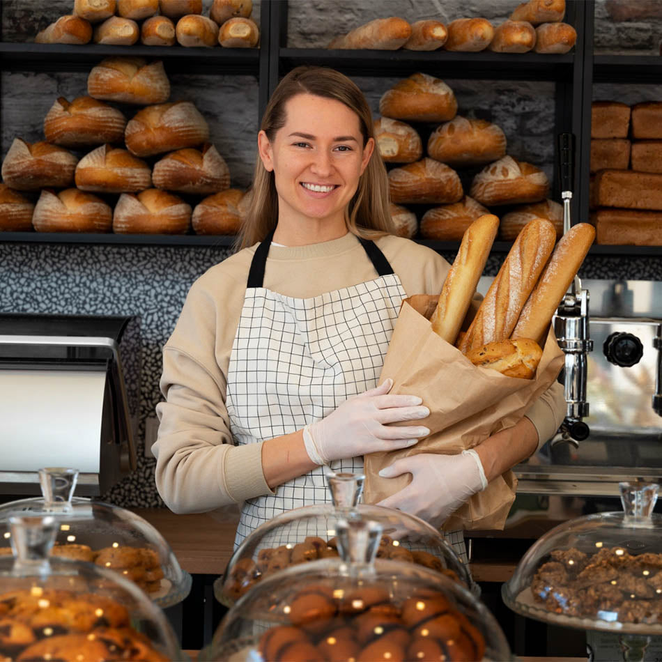 Bakery owner smiling while holding freshly baked bread.
