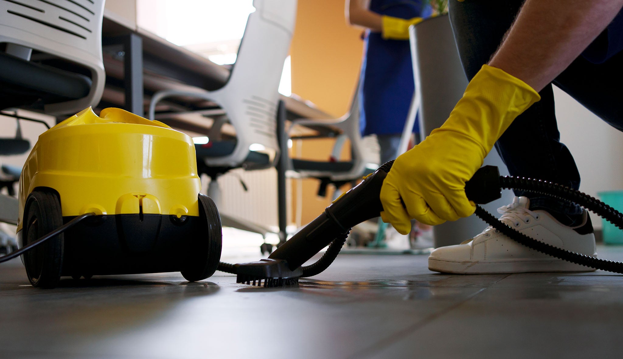 Professional cleaning business worker using a vacuum cleaner in an office.
