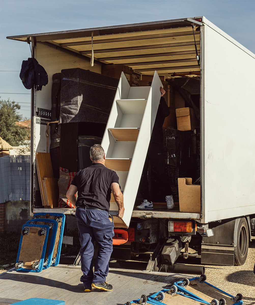Removal company workers loading furniture into the back of a removal lorry.