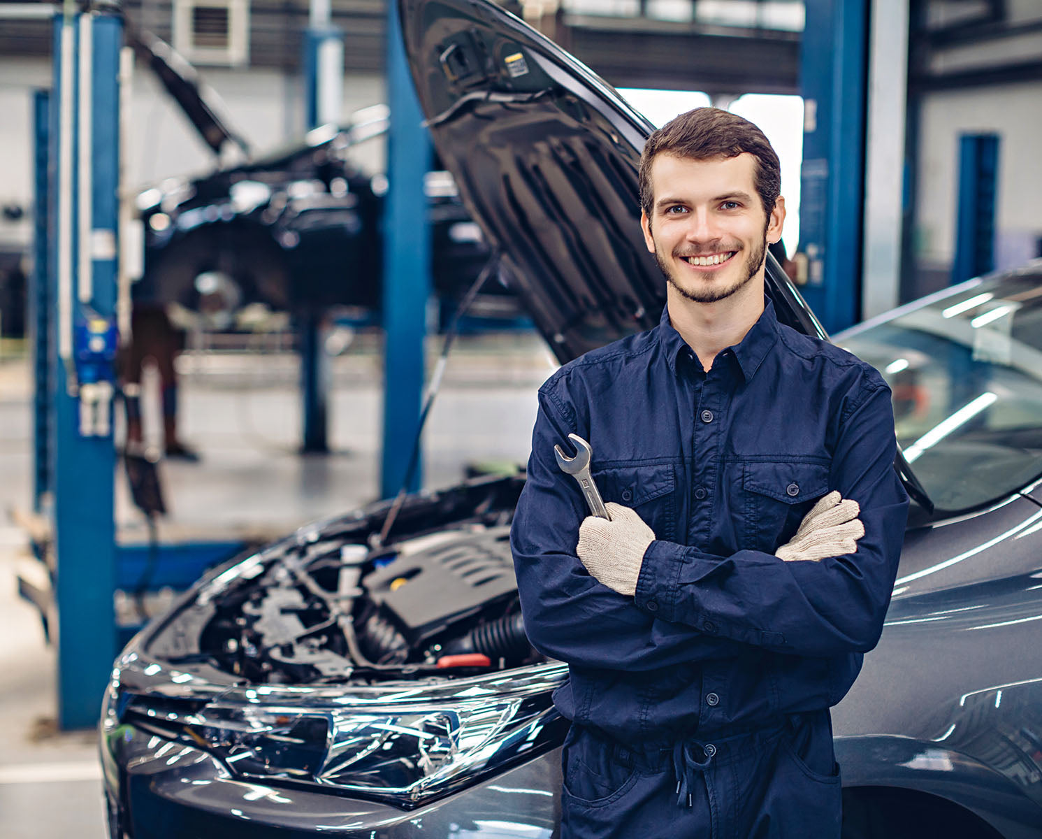 Smiling car mechanic in a small car repair workshop.