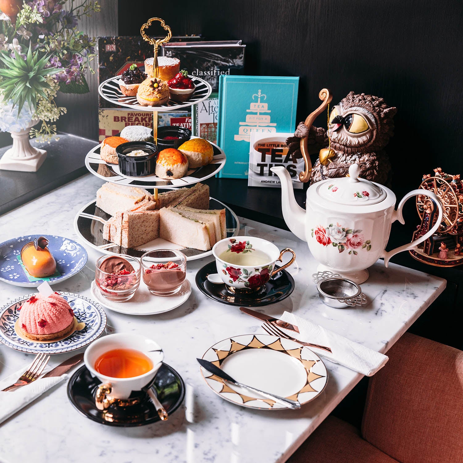 Tea room with afternoon tea including hot tea pastries scones sandwiches mini pies.