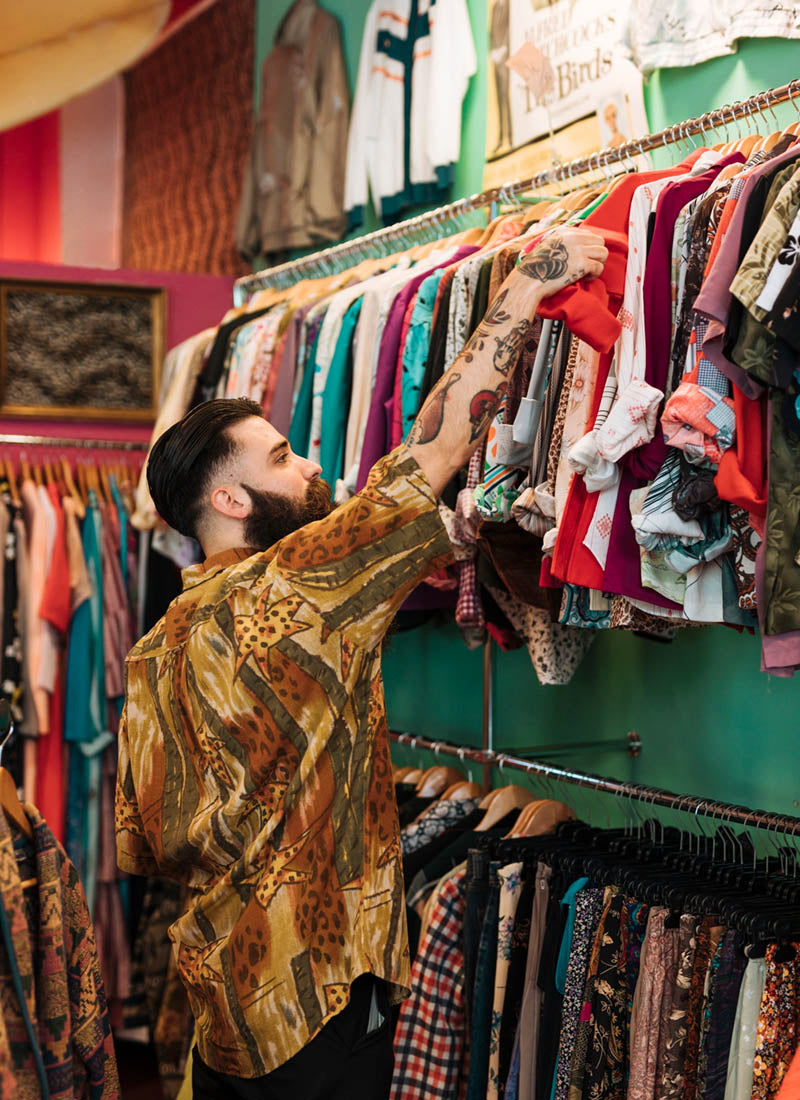 Young male employee adding stock to the shelves in a clothing retail store.