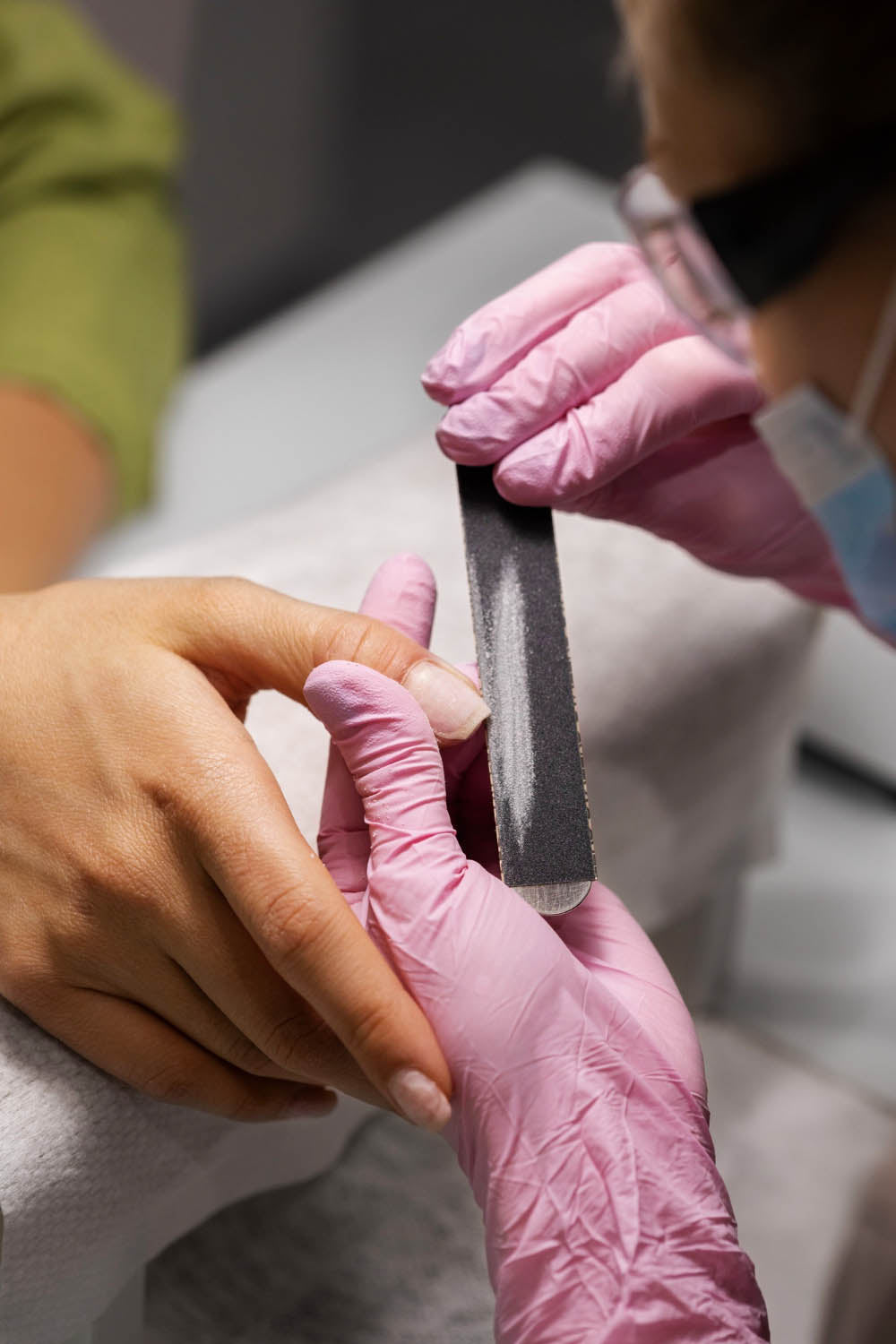A nail technician filing a client's nails.