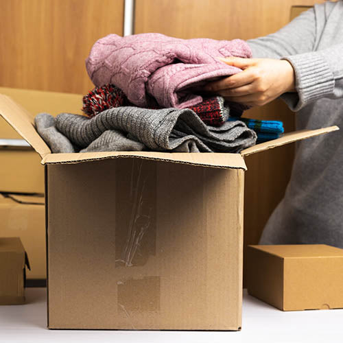 A charity shop volunteer sorting through a box of donations.