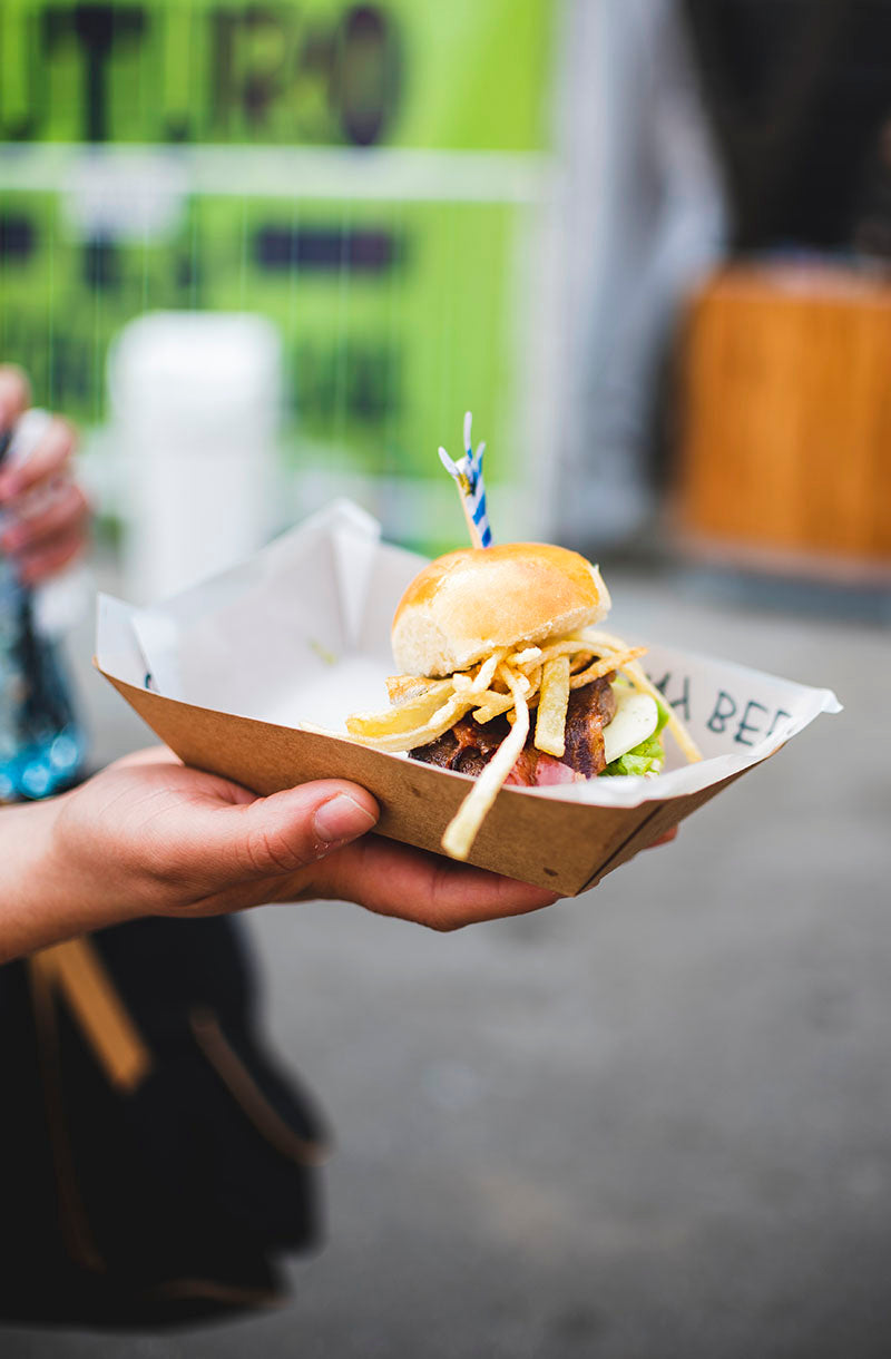 A hand holding a burger from a mobile catering van.