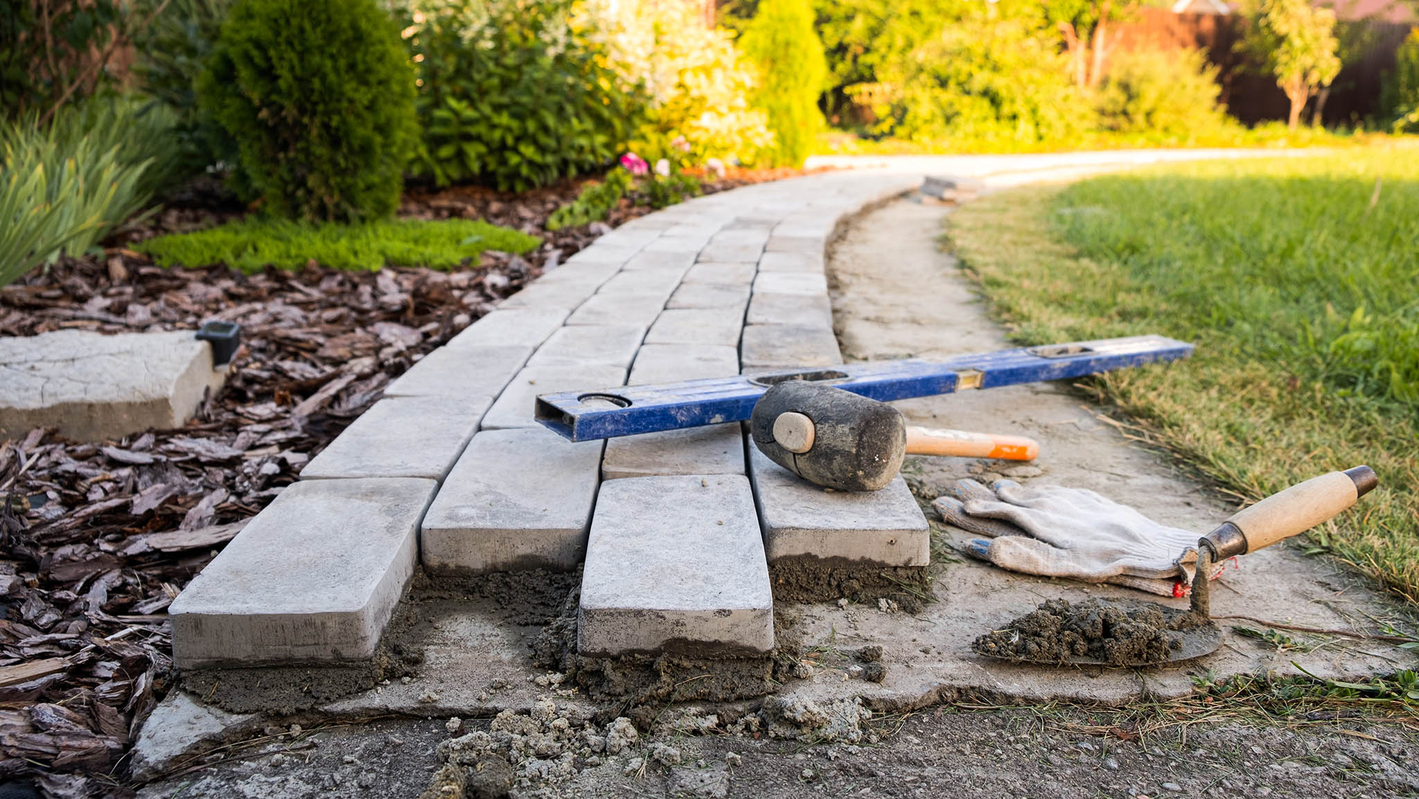A landscape gardening project with paving stones being laid to create a new garden path.