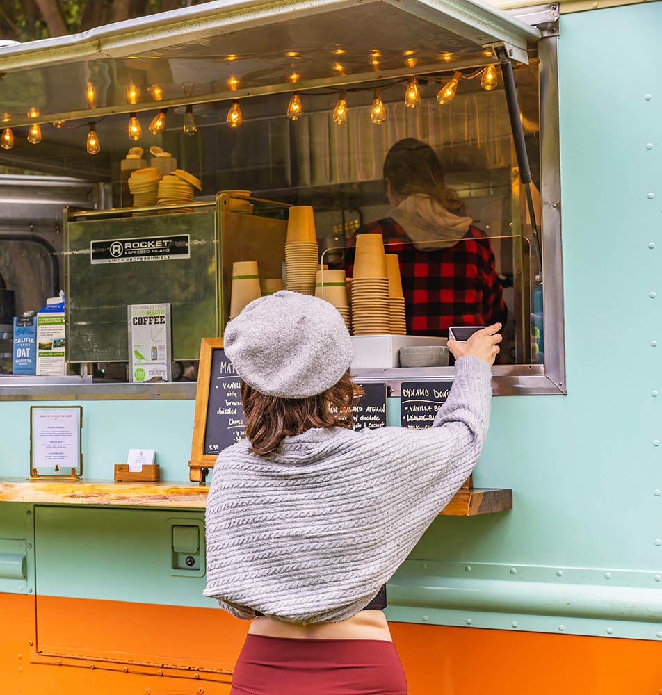 A mobile coffee vendor brewing coffee for a customer.
