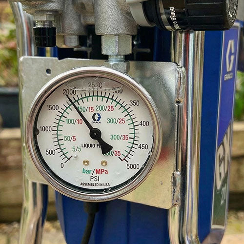 A pressure gauge on an airless paint spraying machine being used for spraying UPVC windows and doors.