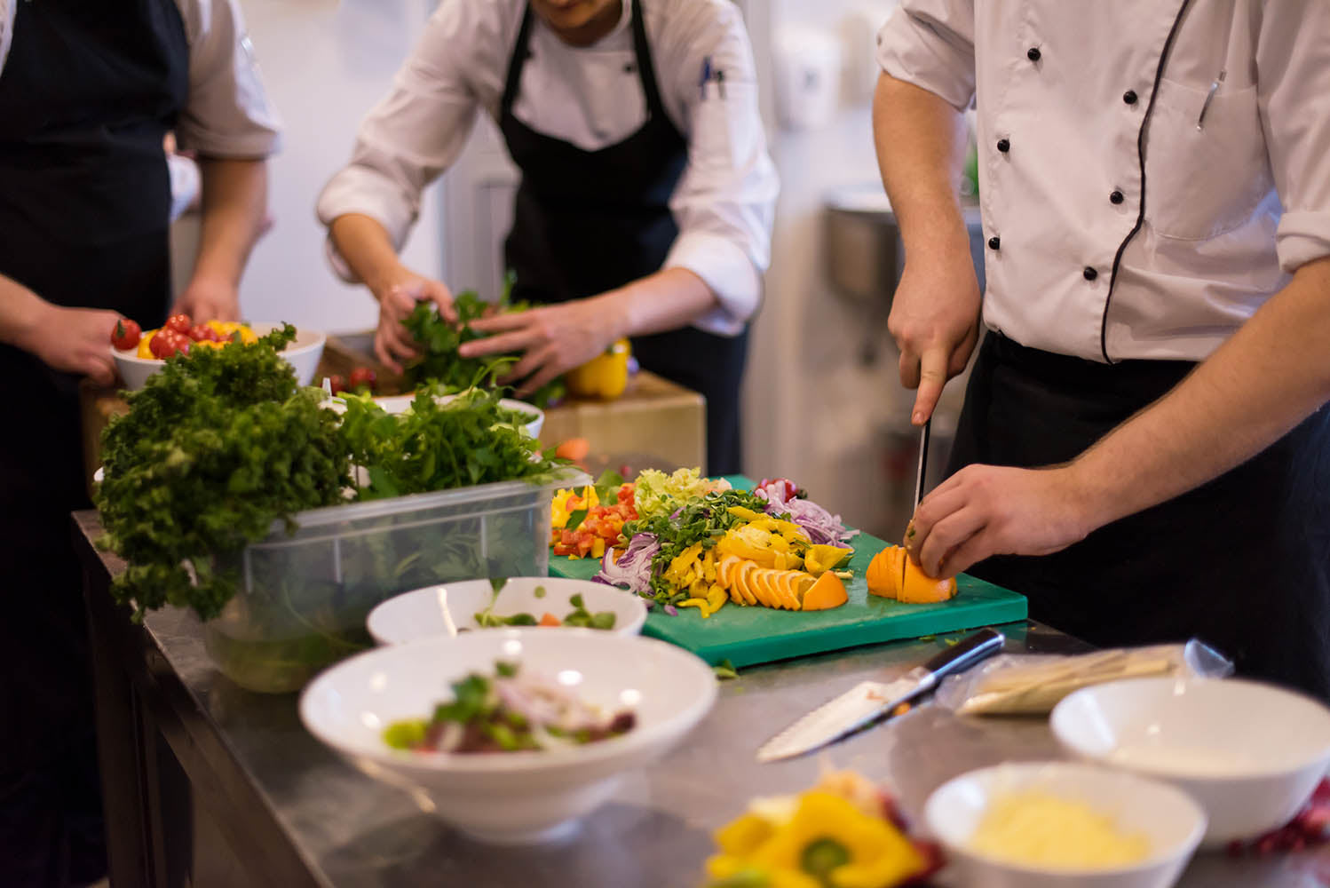 A professional event catering kitchen with chefs preparing food for a corporate event.
