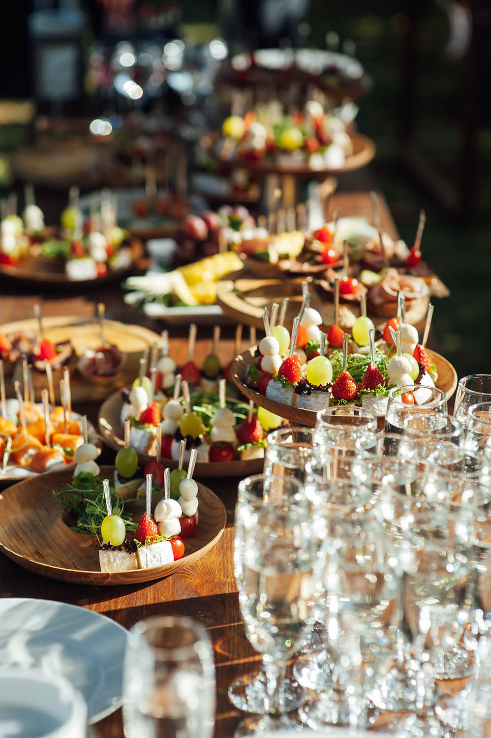 A table at a catered event with various snacks, sandwiches, strawberries and champagne glasses.