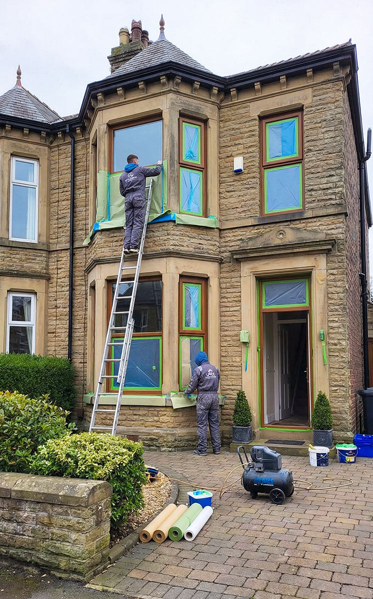 A UPVC spraying team masking up a large victorian house ready to spray paint the UPVC windows and doors.