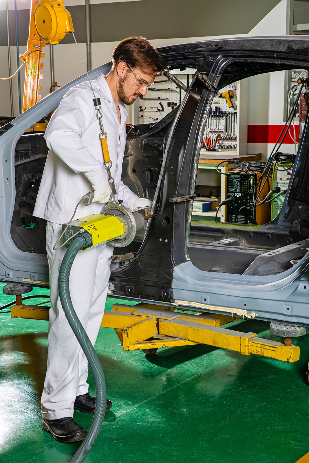 An auto body repair technician working spot welding car body panels in a car body shop.
