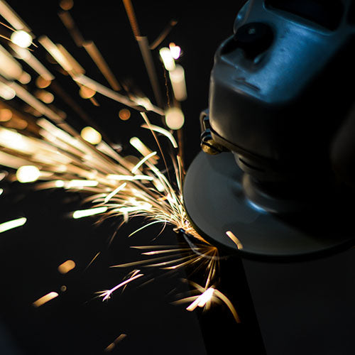 Car body shop worker using a grinder on a car body panel.