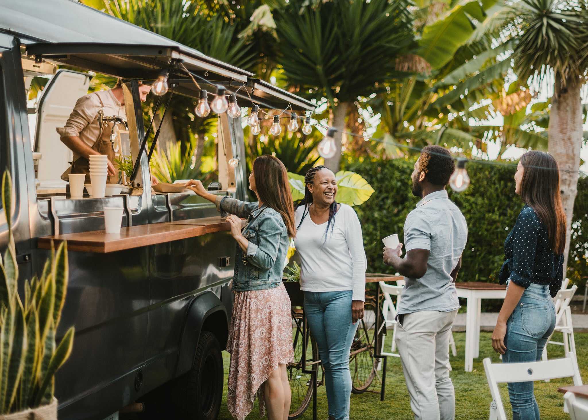 Chef in a mobile food restaurant serving customers outdoors.