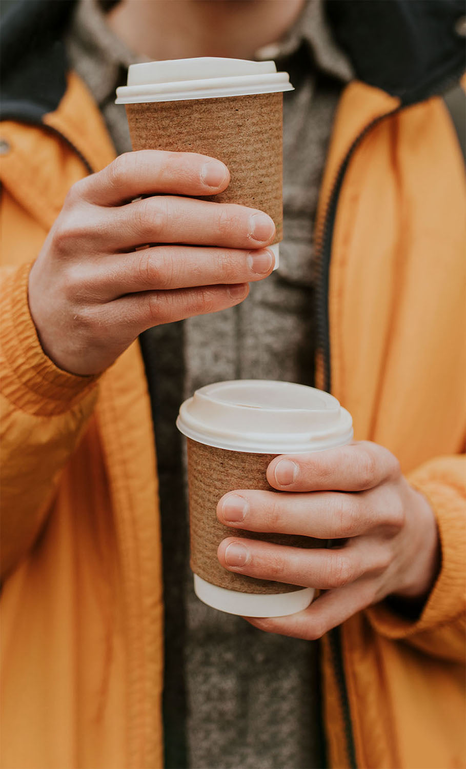 Customer holding takeaway coffee cups bought from a mobile coffee shop.
