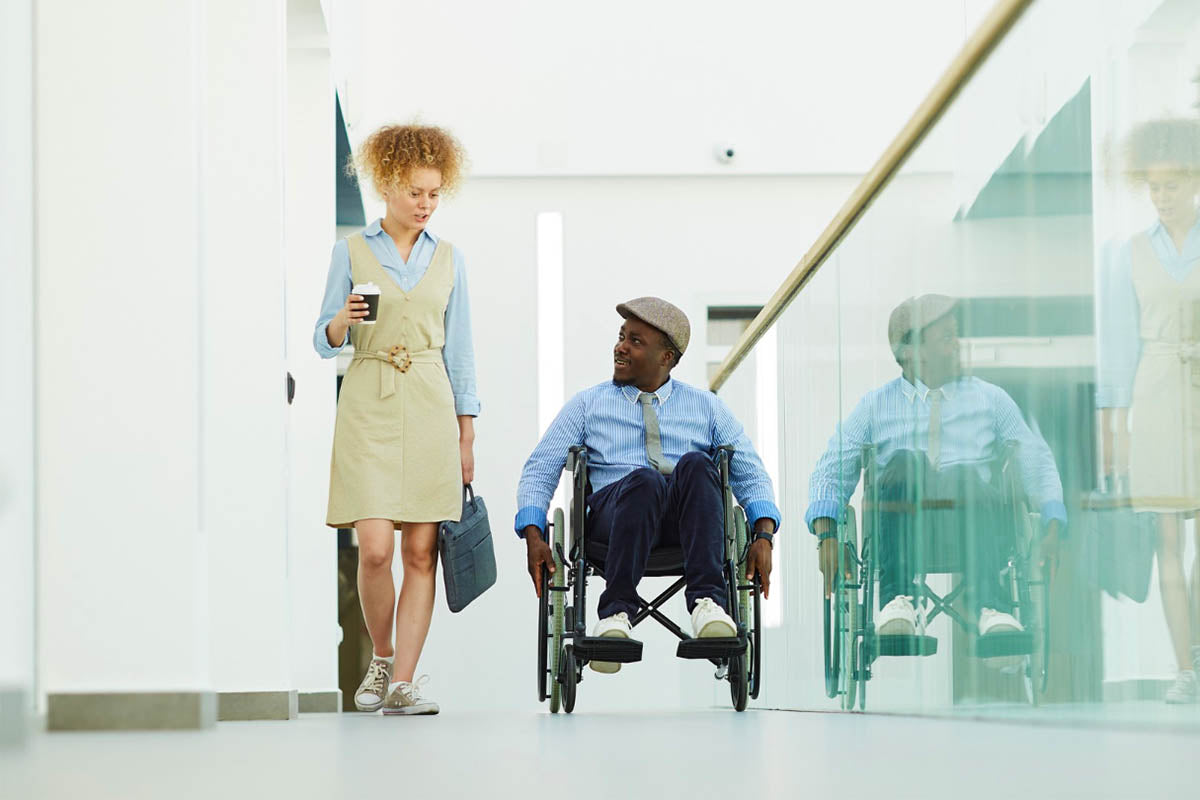 Person in wheelchair talking to colleague in the workplace