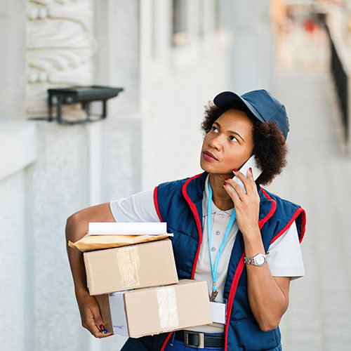Female courier carrying packages whilst talking on her phone.