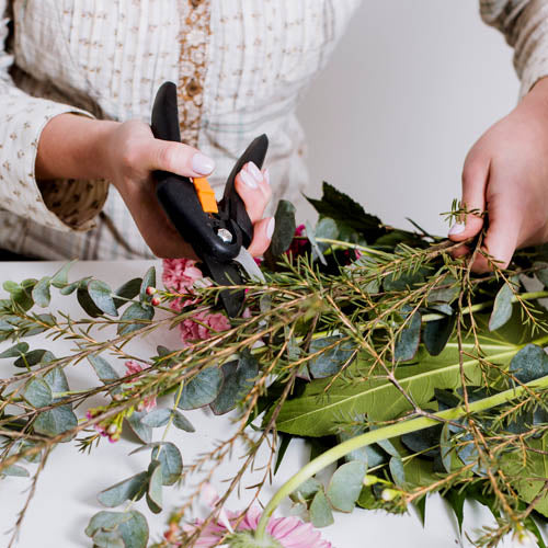 Florist cutting branches from a bunch of plants.
