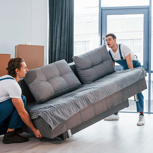 Furniture removal employees lifting heavy sofa.