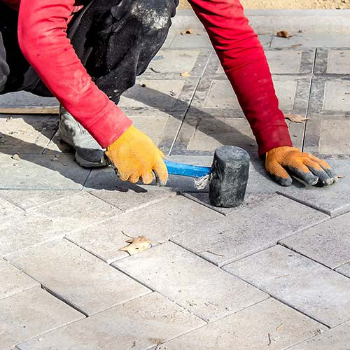 Landscape gardener at work laying paving slabs.