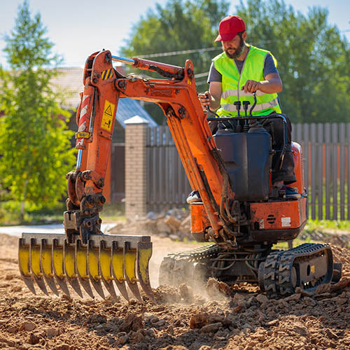 Landscape gardener operating plant machinery on a garden construction site.