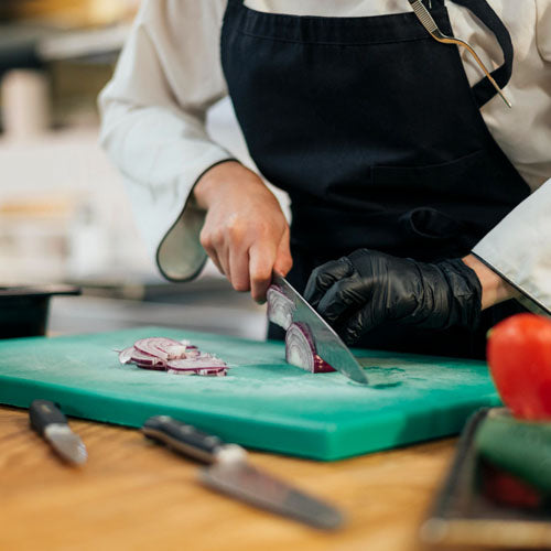 Takeaway chef chopping onions in a kitchen.