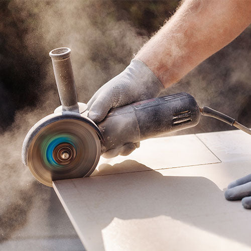 Bathroom fitter cutting moisture resistant plasterboard during a bathroom installation, creating high levels of dust and highlighting the need for dust control and suitable PPE.