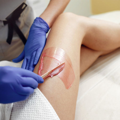 Beautician performing hot wax hair removal on a female client.