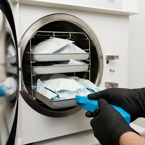 Packaged sterile instruments being loaded into an autoclave during the sterilisation process in a body piercing studio.