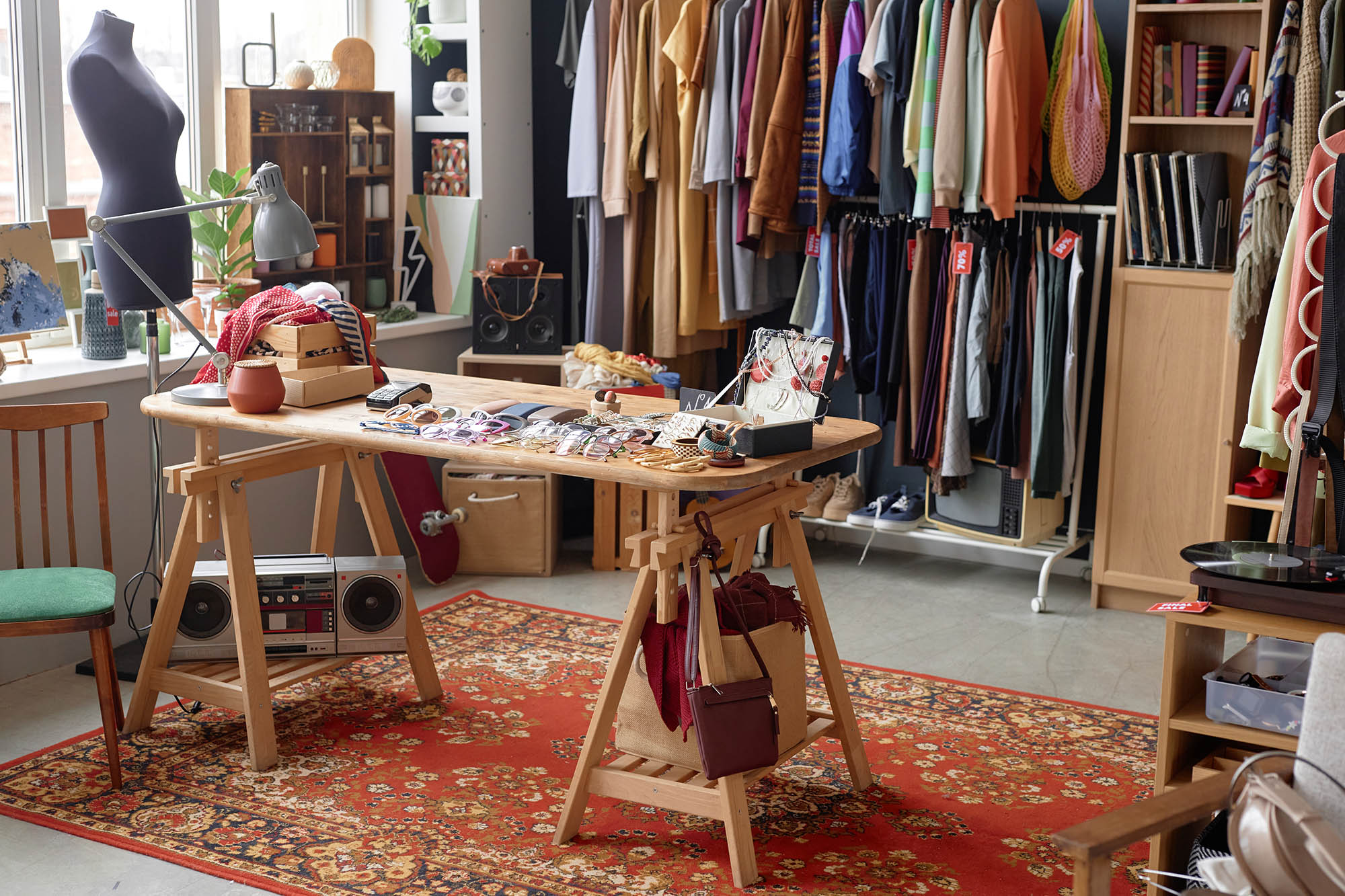 Interior of a charity shop with second-hand clothing, accessories and display tables.