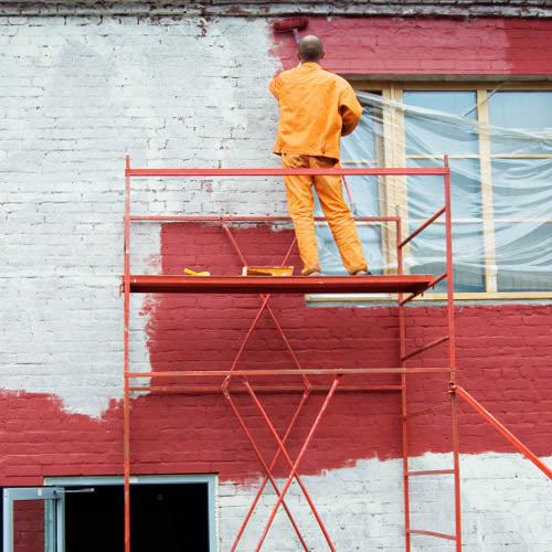 Decorator working at height painting an exterior wall