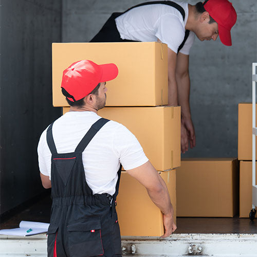Delivery man lifting large boxes from the back of a delivery lorry.