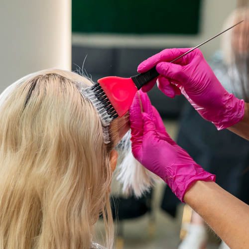 Hair stylist applying bleach to client's hair