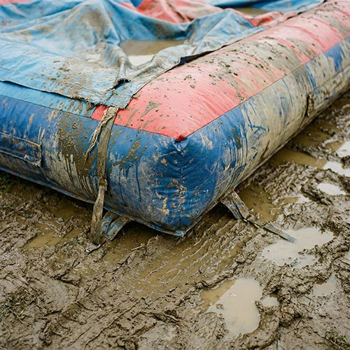 Inflatable hire equipment on muddy ground in wet weather, showing weather-related hazards and poor ground conditions during outdoor inflatable use.