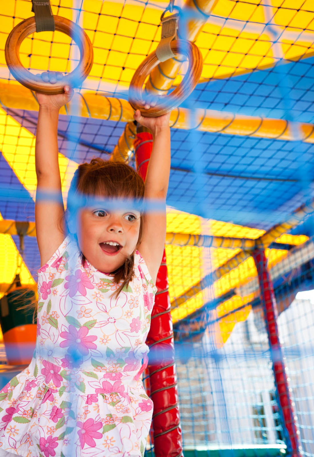 little girl hanging from rings in a soft play centre