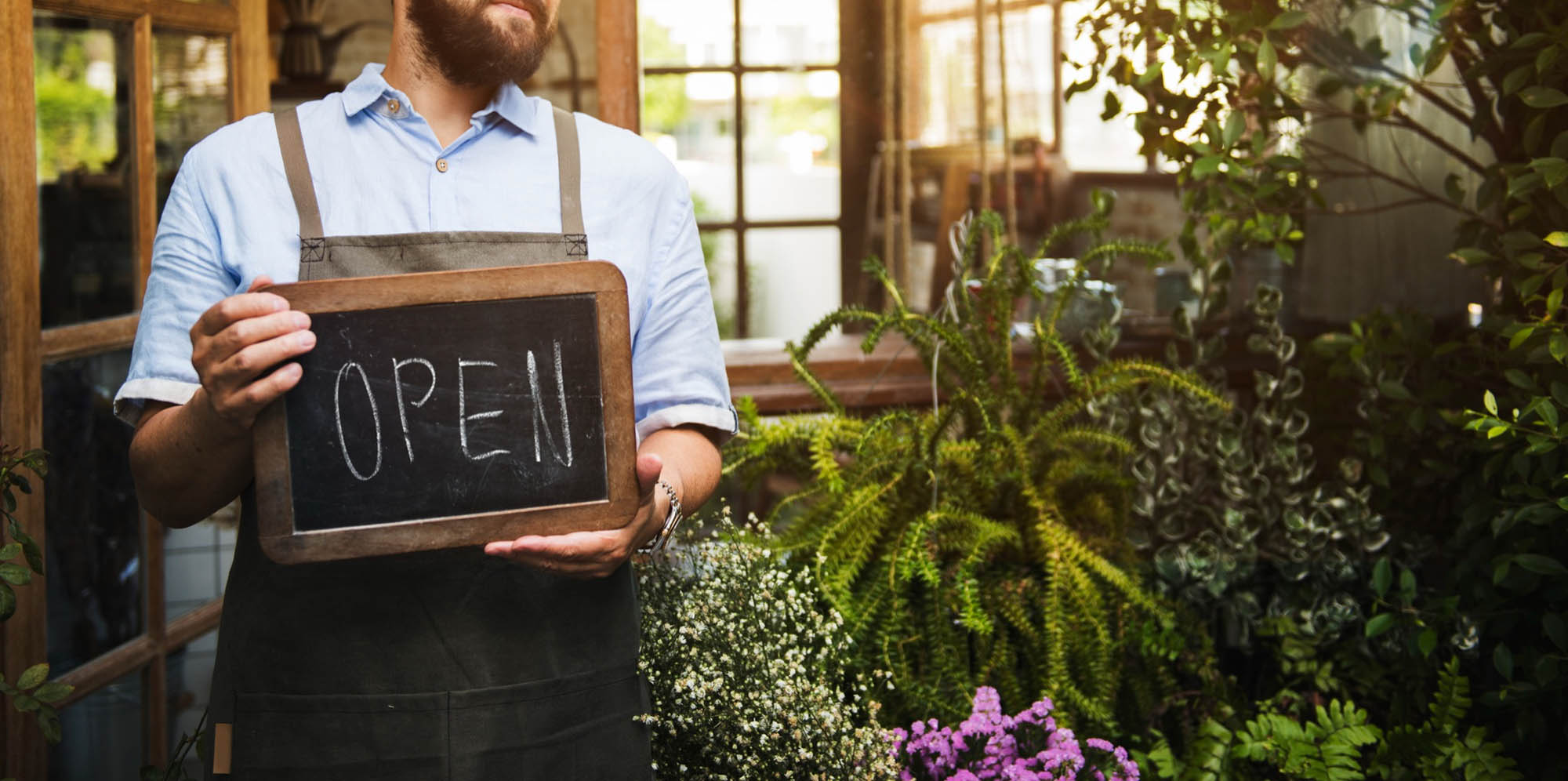 A small business owner holding an open for business sign