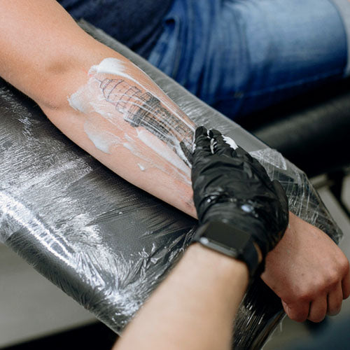 Tattooist cleaning the arm of a client after a fresh tattoo