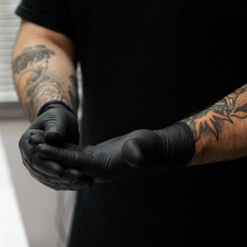 Tattoo artist wearing black protective gloves