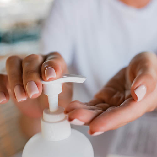 A nail technician applying hand gel to her hands.